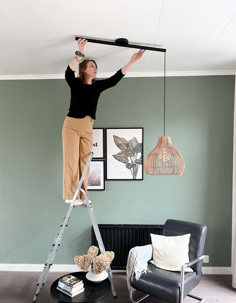 Woman adjusting Ligtswing so the pendant light hangs in the right place above the reading corner