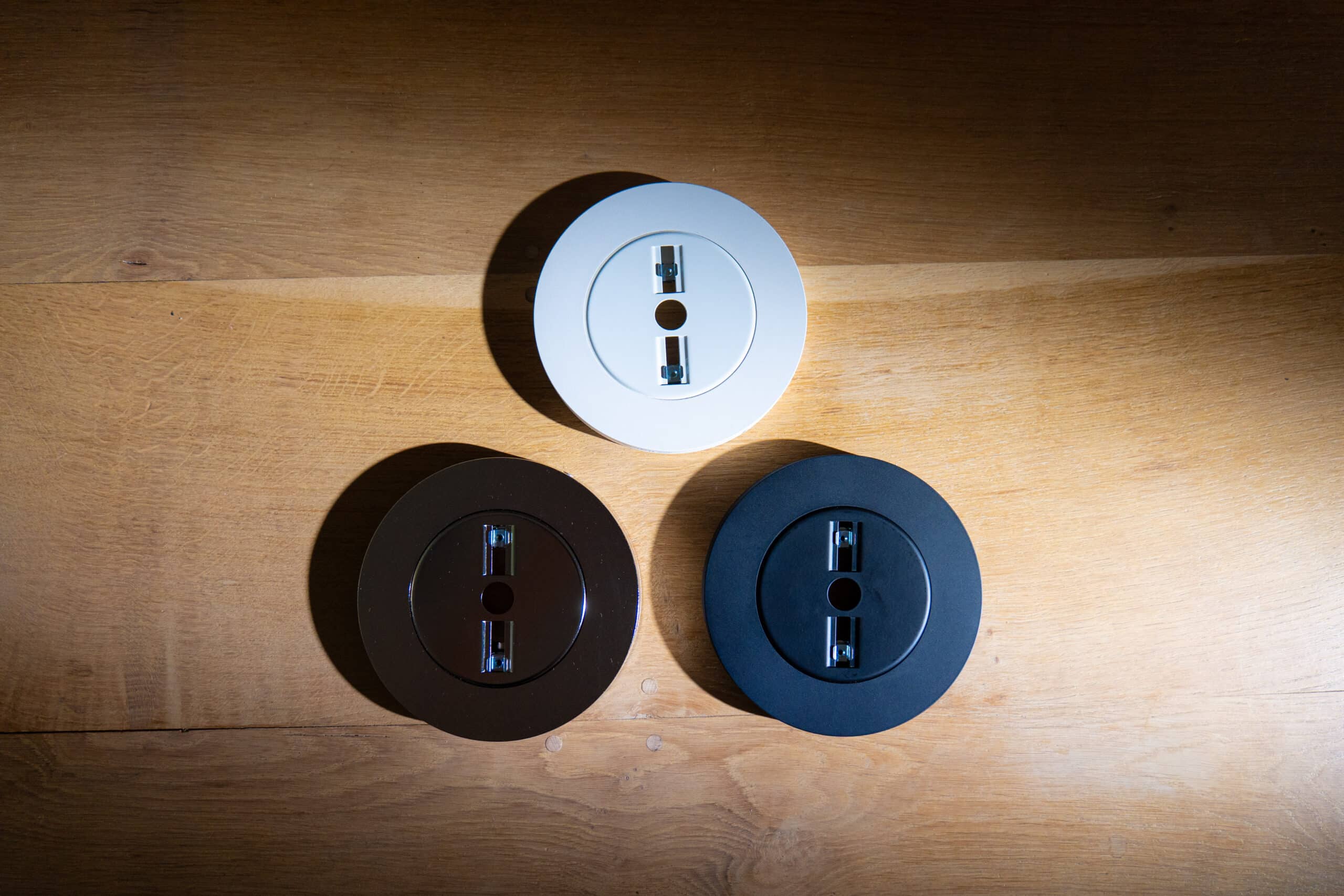 Lightswing® Zero in three colors: white, brown, and black on wooden background