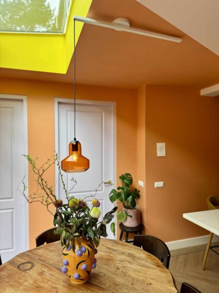 Lightswing® Single Matt White mounted on slanted ceiling with pendant light above round wooden dining table